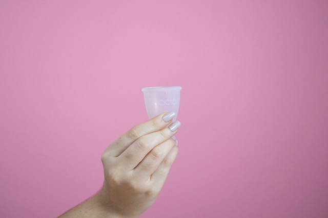 月経カップをもつ女性の手と透明の月経カップ